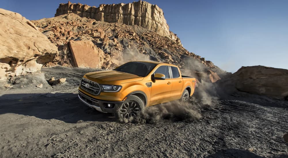 An orange 2021 Chevy Colorado is shown driving on a desert road during a 2021 Ford Ranger vs 2021 Chevy Colorado comparison.