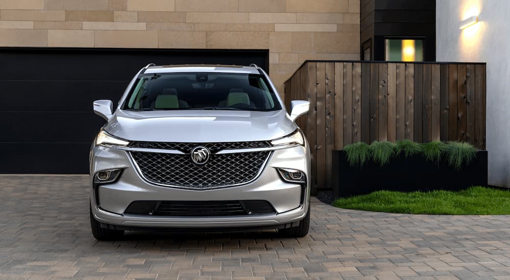 A silver 2022 Buick Enclave Avenir is shown parked outside of a modern home.