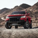 A red 2022 Chevy Colorado ZR2 is shown parked on a dirt path during a 2022 Chevy Colorado vs 2022 Nissan Frontier comparison.