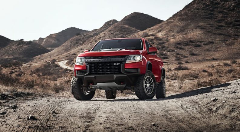 A red 2022 Chevy Colorado ZR2 is shown parked on a dirt path during a 2022 Chevy Colorado vs 2022 Nissan Frontier comparison.