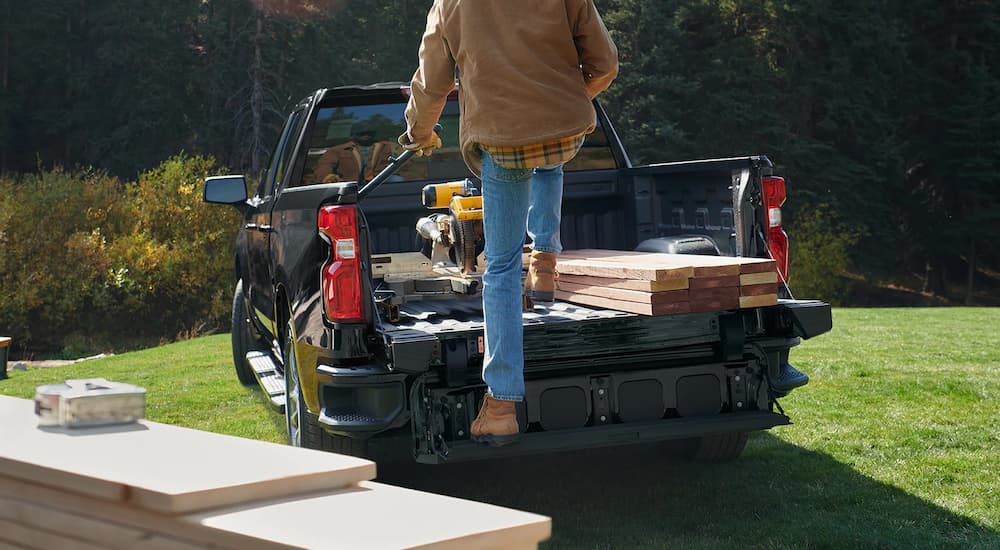 A man is shown using the Multi-Flex gate to step into the bed of a black 2022 Chevy Silverado 1500.