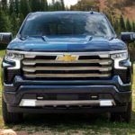 A blue 2022 Chevy Silverado 1500 High Country is shown from the front parked on a grassy area.