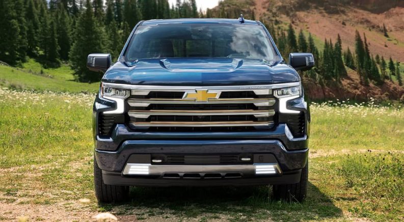 A blue 2022 Chevy Silverado 1500 High Country is shown from the front parked on a grassy area.