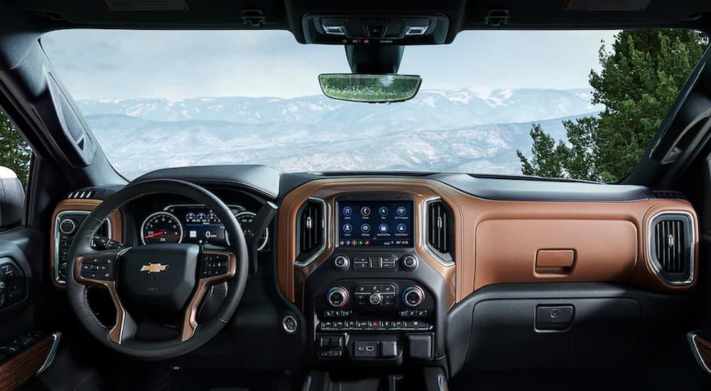 The black and tan interior of a 2022 Chevy Silverado 1500 Limited shows the steering wheel and infotainment screen.