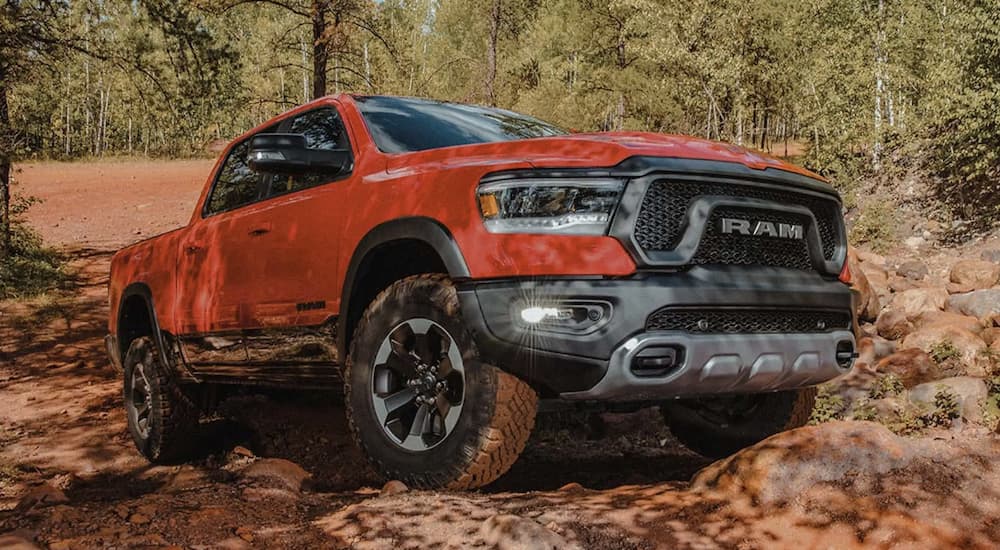 An orange 2022 Ram 1500 is shown parked in the woods.