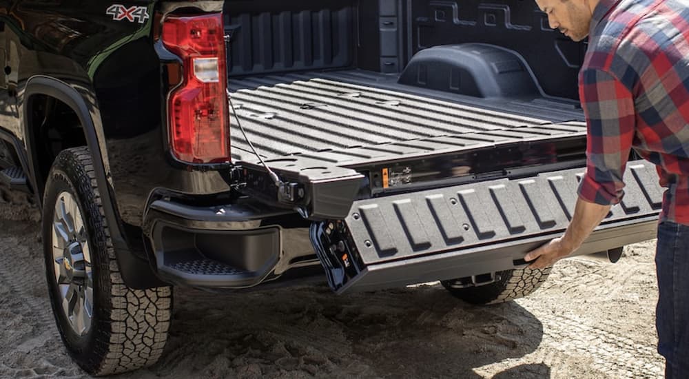 A person is shown opening the tailgate on a black 2022 Chevy Silverado 2500 HD.