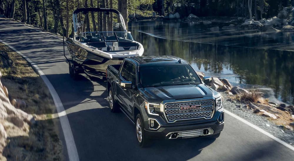 A black 2022 GMC Sierra 1500 Limited is shown towing a boat near a body of water.