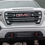 A white 2022 GMC Sierra 1500 is shown from the front off-roading in the mountains after winning a 2022 GMC Sierra 1500 vs 2022 Ram 1500 comparison.