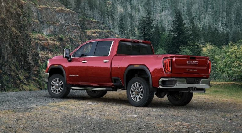 A red 2022 GMC Sierra 3500HD is shown from a rear angle parked in a forest.