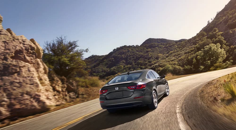 A grey 2022 Honda Insight EX is shown from the rear driving up a mountain highway.