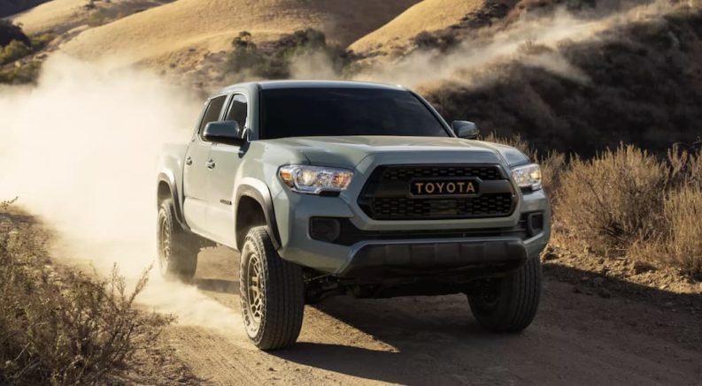 A green 2022 Toyota Tacoma SR5 Double Cab is shown driving on a dirt road.