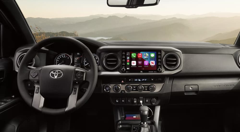 The black interior of a 2022 Toyota Tacoma TRD shows the steering wheel and infotainment screen.