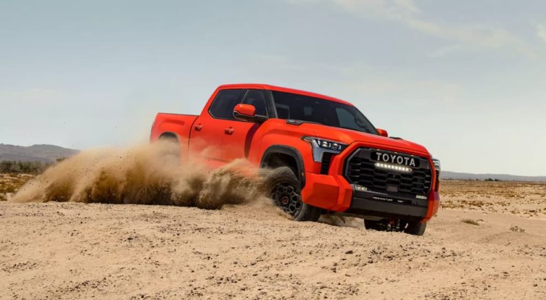 An orange 2022 Toyota Tundra TRD Pro CrewMax is shown off-roading in a desert.