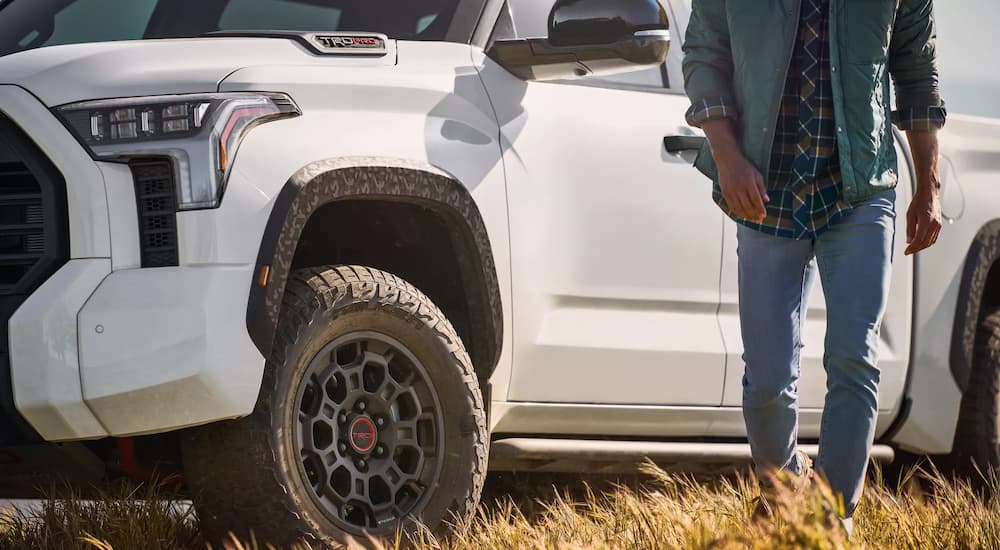 A man is shown walking away from a white 2022 Toyota Tundra TRD Pro CrewMax parked in a grassy field.