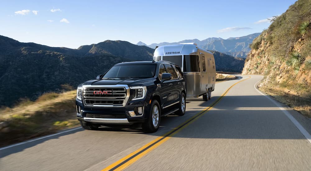 A black 2021 GMC Yukon is shown towing a silver camper after leaving a GMC dealer.