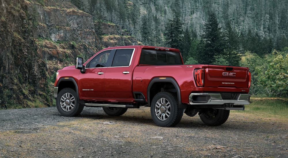 A red 2022 GMC Sierra 3500HD is shown from a rear angle parked near a forest.