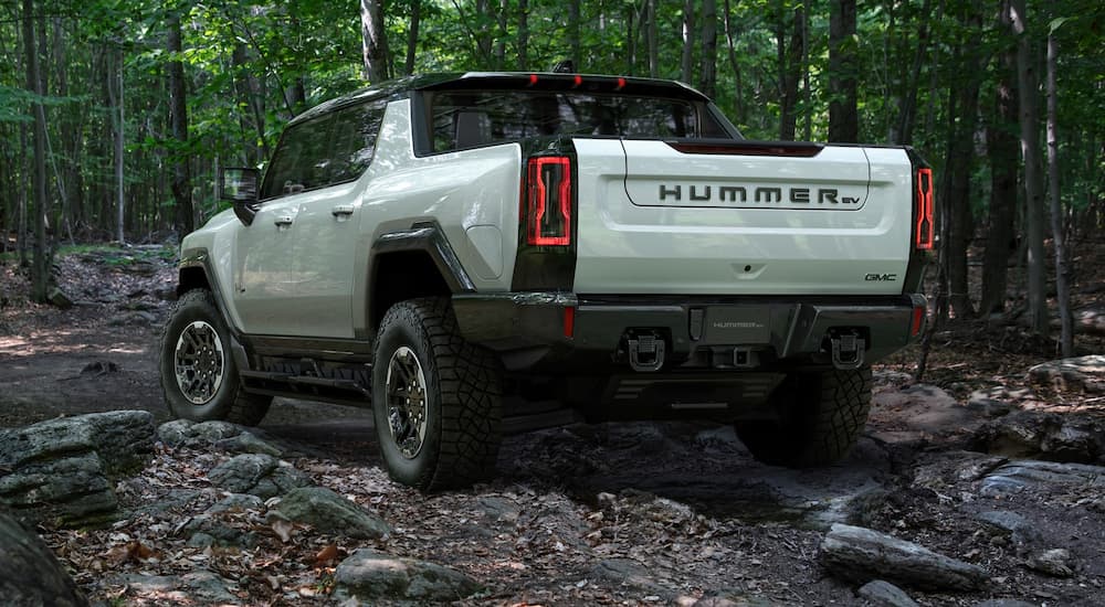 A silver 2022 Hummer EV truck is shown from the rear off-roading in the woods after visiting a GMC dealer.