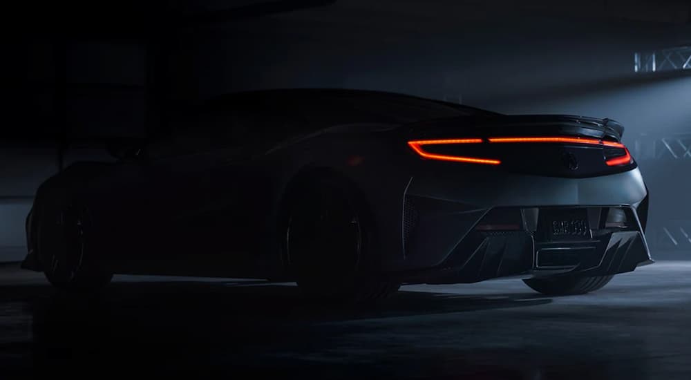 A silver 2022 Acura NSX is shown in a dark area at a Honda dealership.
