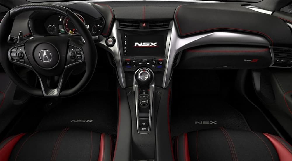The black and red interior of a 2022 Acura NSX shows the steering wheel and center console.