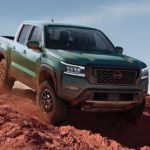 A green 2022 Nissan Frontier PRO-4X is shown driving on a dusty off-road trail.