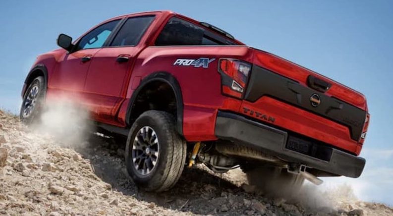 A popular certified pre-owned Nissan, a red 2020 Nissan Titan Pro 4x is shown from the rear off-roading in a desert.