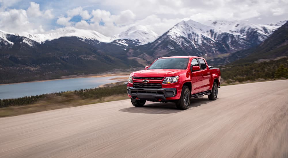A red 2022 Chevy Colorado Trail Boss is shown from the front at an angle while driving down a dirt road.