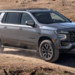 A grey 2022 Chevy Suburban is shown from the side off-roading in the desert.