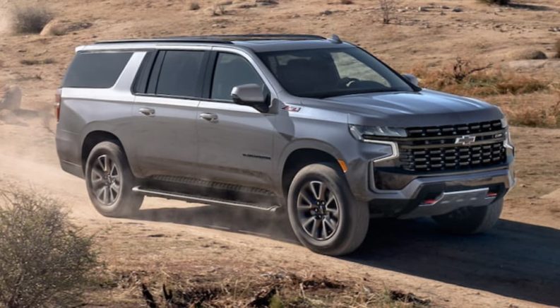 A grey 2022 Chevy Suburban is shown from the side off-roading in the desert.