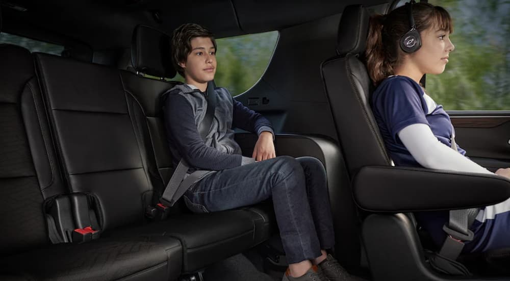The black interior of a 2022 Chevy Tahoe shows two children riding comfortably in the spacious cabin.