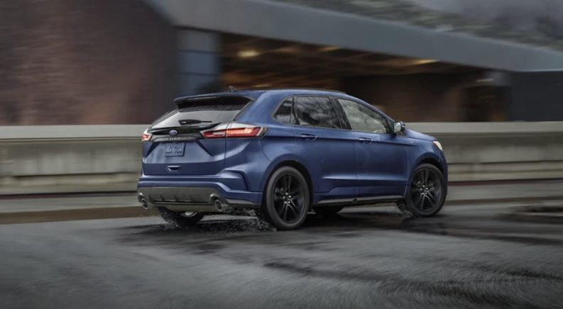 A blue 2022 Ford Edge is shown from the rear driving on an open road.