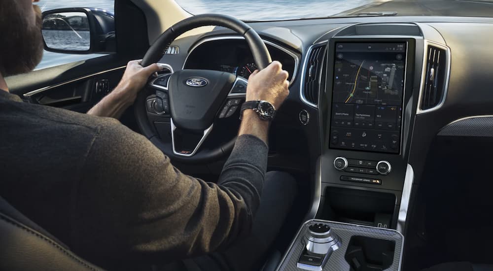 The black interior of a 2022 Ford Edge shows the steering wheel and infotainment screen.