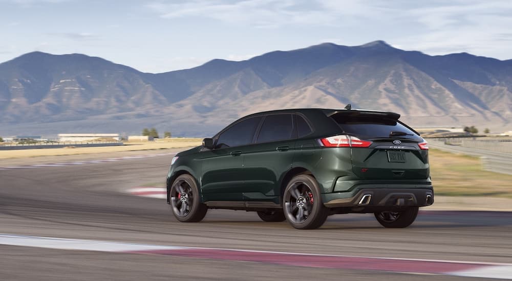 A green 2022 Ford Edge ST is shown from a rear angle driving on a track.