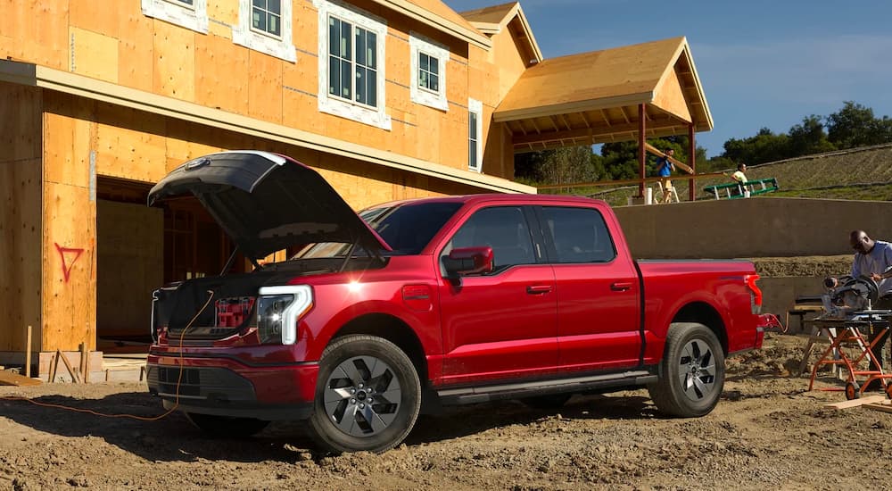 A red 2022 Ford F-150 Lightning is shown at a construction site with the frunk open.