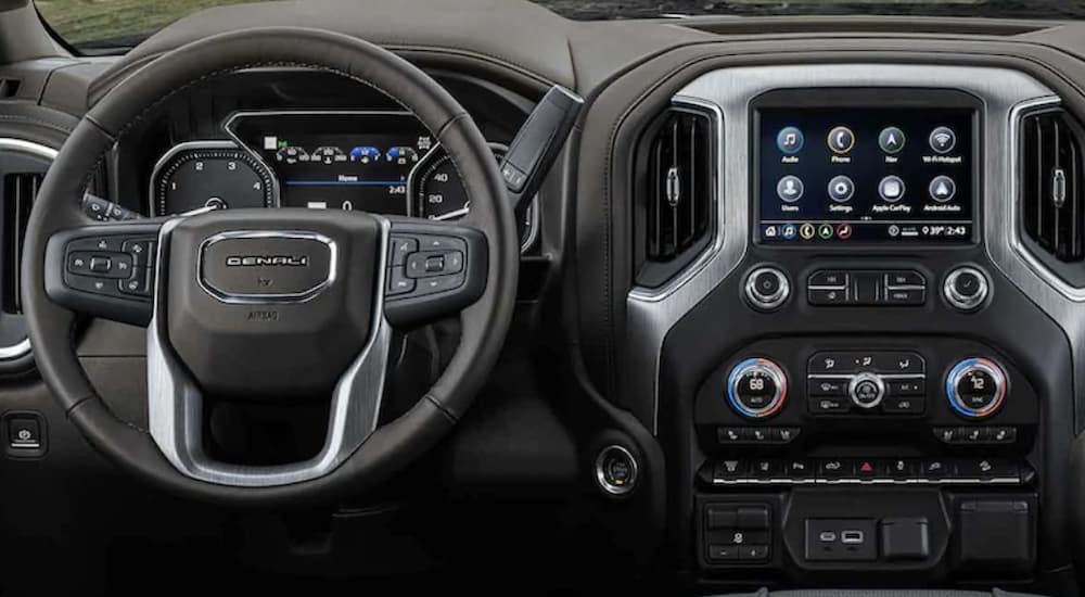 The black interior of a 2022 GMC Sierra 3500HD Denali shows the steering wheel and infotainment screen.