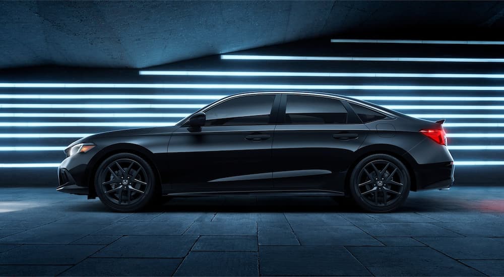 A black 2022 Honda Civic Si is shown from the side against a lighted wall.