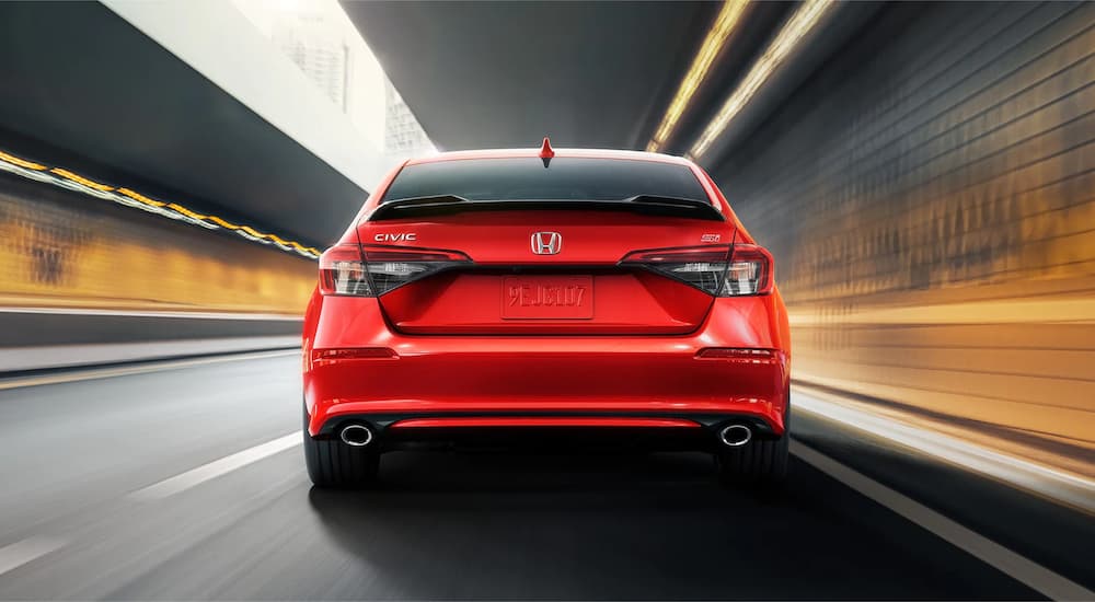 A red 2022 Honda Civic Si is shown from the rear driving through a tunnel.