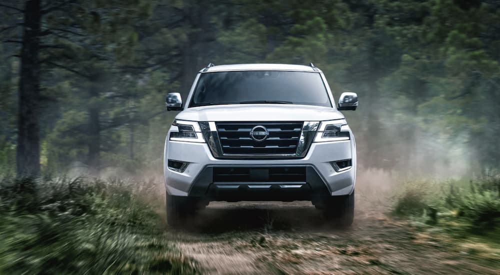 A white 2022 Nissan Armada is shown from the front off-roading in a forest.