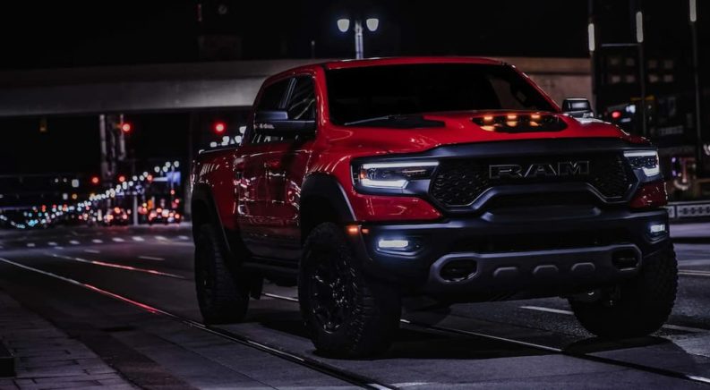 A red 2022 Ram 1500 TRX is shown driving through a city at night.