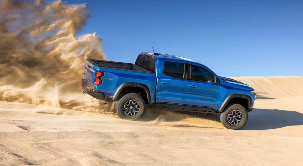A blue 2023 Chevy Colorado ZR2 is shown kicking up sand.