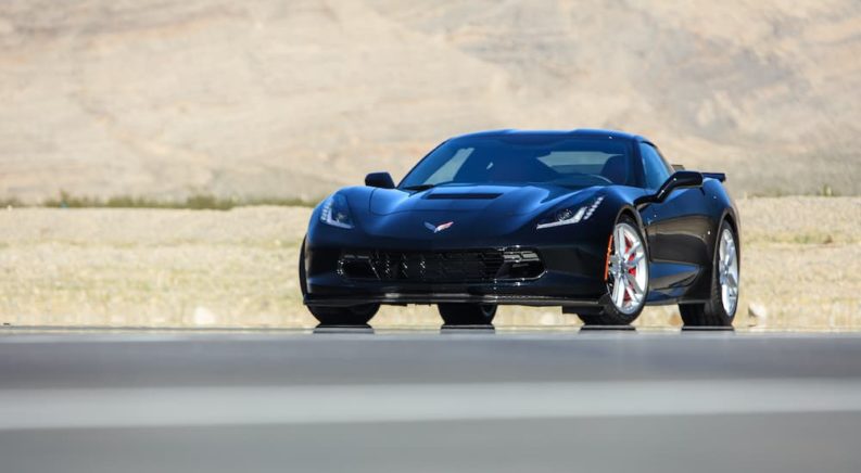 A black 2020 Chevy Corvette Z51 is shown from the front parked on tarmac after visiting a Chevy dealer.