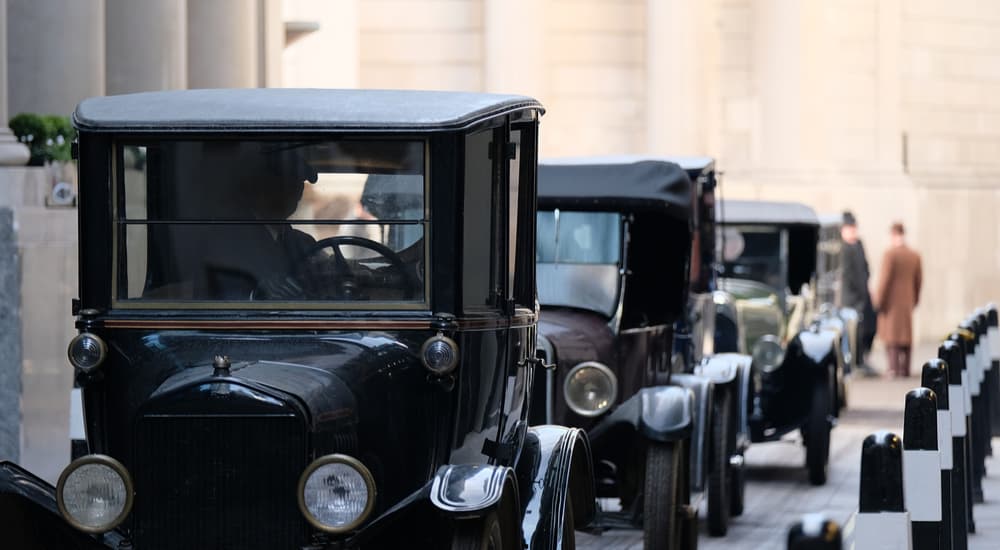 A row of old cars are shown on a city street.