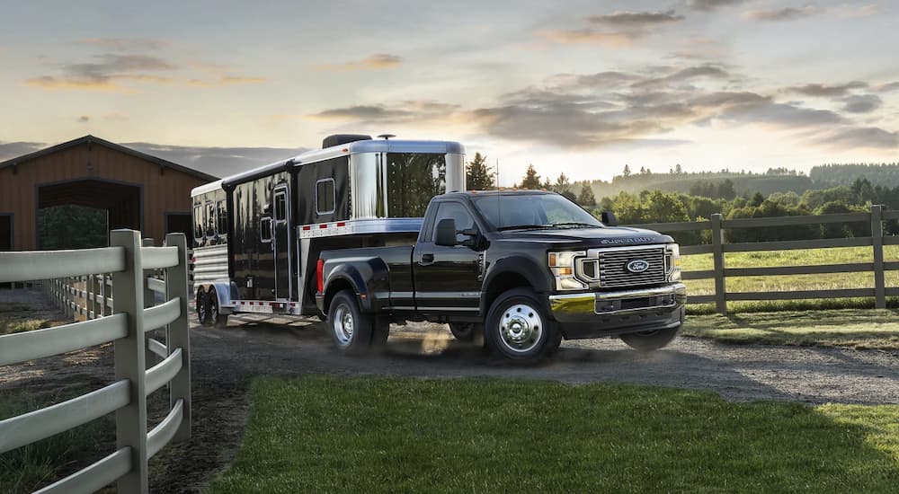 A black 2022 Ford F-450 Super Duty is shown towing a horse trailer.