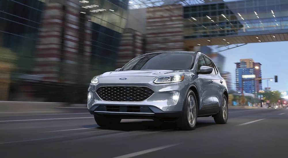 A silver 2022 Ford Escape Titanium Plug-In Hybrid is shown driving on a city street.