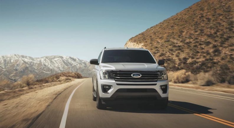 A white 2022 Ford Expedition XL STX is shown driving down a highway after visiting a Ford dealer.