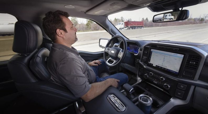 A person is shown driving hands free with Ford's BlueCruise.