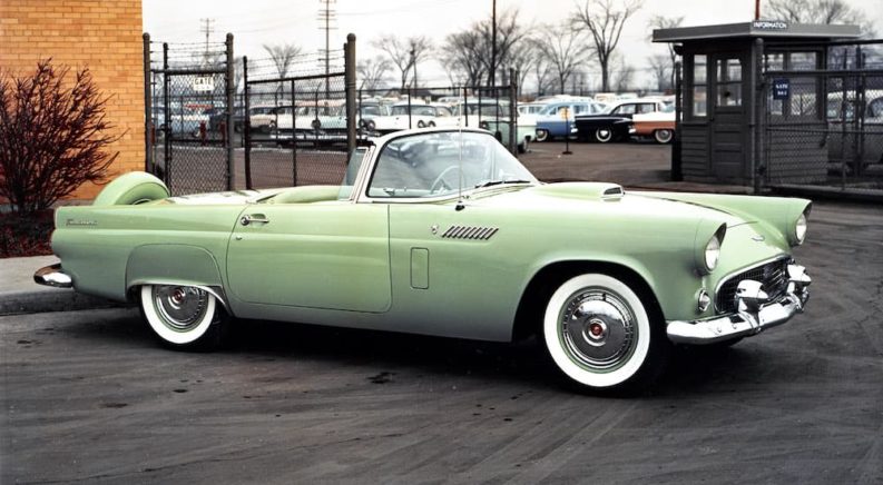 A green 1956 Ford Thunderbird is shown parked at a Ford dealership.