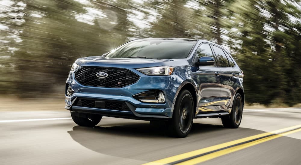 A blue 2019 Ford Edge ST is shown from the front driving on an open road.