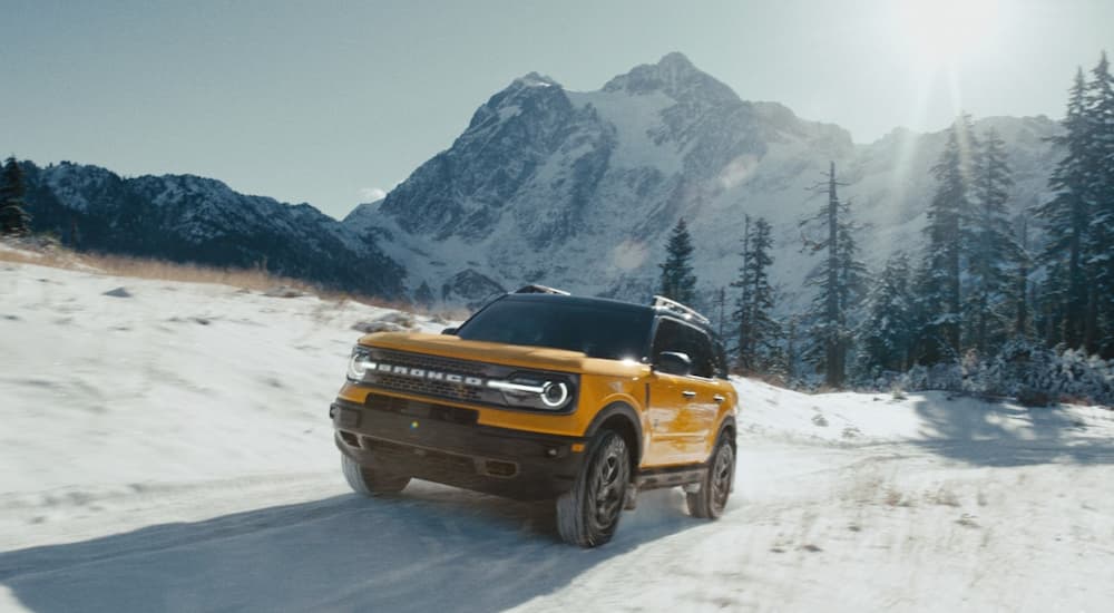 A yellow 2022 Ford Bronco Sport is shown driving on a snow-covered trail.