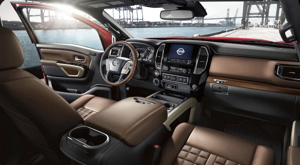 The brown interior of a 2021 Nissan Titan shows the steering wheel and infotainment screen.