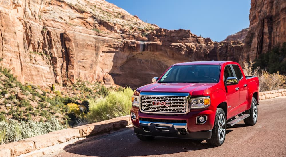 A red 2019 GMC Canyon Denali is shown in the mountains after leaving a used GMC dealer.